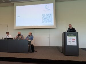 Panelists Markus Hilger, Jonathon Anderson, and Travis Cotton with moderator Chris Simmons at the podium during the OpenHPC BoF session